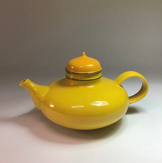 Yellow teapot with a matching lid on a gray background