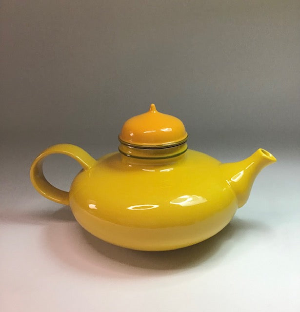 Yellow teapot with a matching lid on a gray background