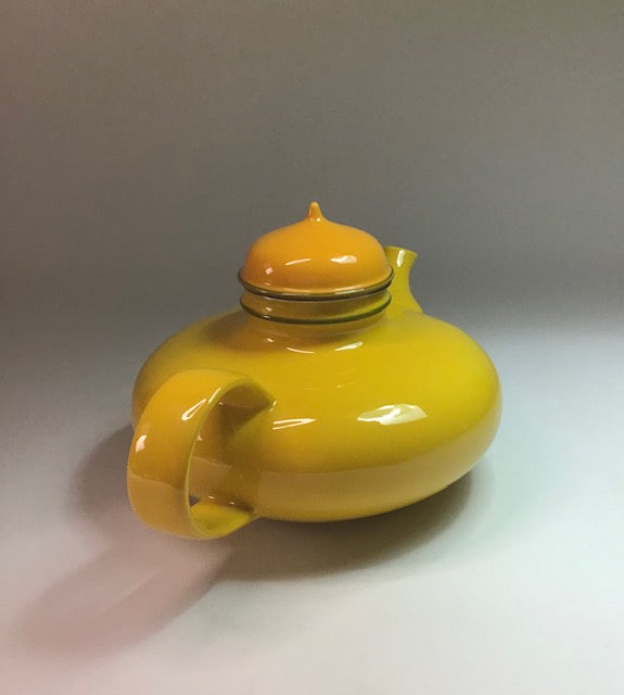 Yellow teapot with a lid on a light gray background