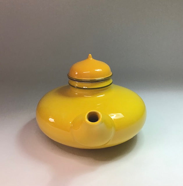 Yellow ceramic jar with a lid on a light gray background