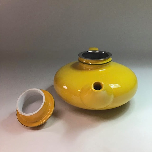 Yellow ceramic pot with a white interior on a gray background