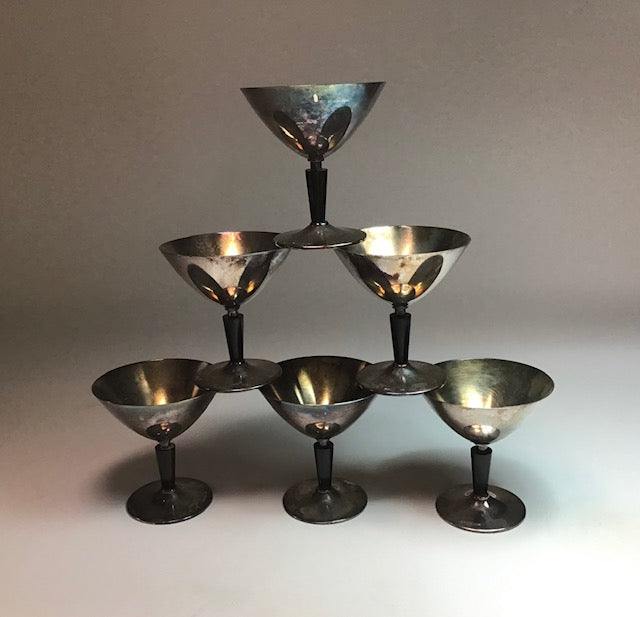 Set of six silver cocktail glasses arranged in a pyramid formation on a neutral background