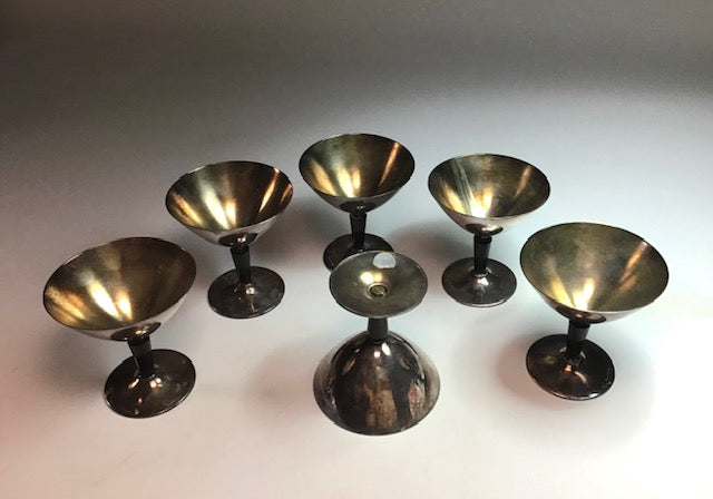 Set of six metallic candle holders on a light gray background