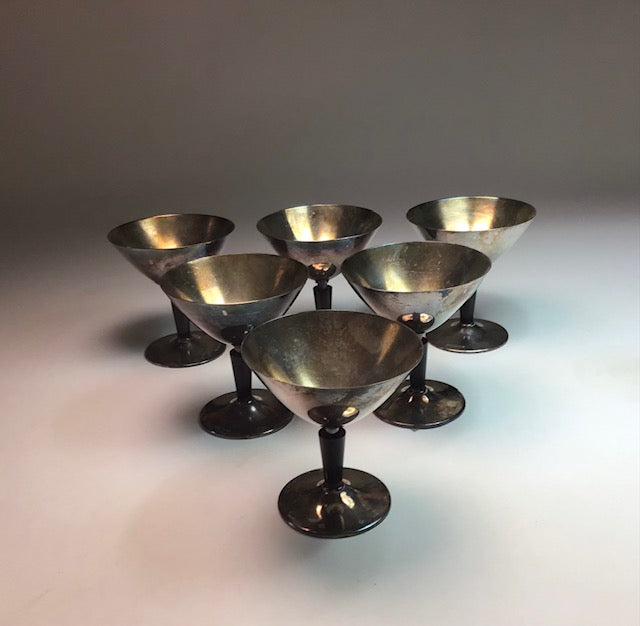 Set of six metallic cocktail glasses on a gradient background