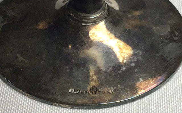 Close-up of a metallic object with 'Gianfranco Ferre' branding on a textured surface.