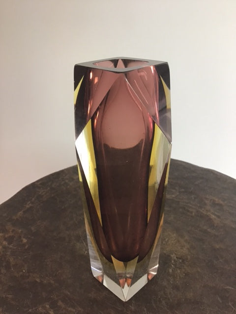 Faceted crystal on a dark surface with a white background