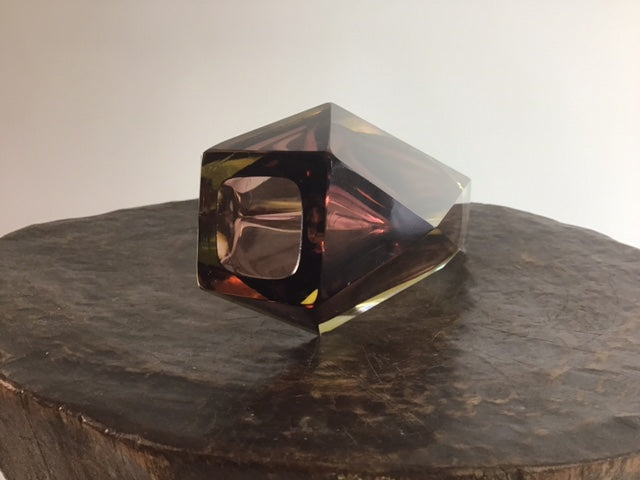 Transparent geometric object on a dark surface with a neutral background