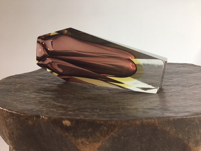 Modern glass sculpture on a dark surface with a neutral background