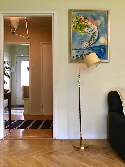 Living room with a lamp, painting, and view into another room.