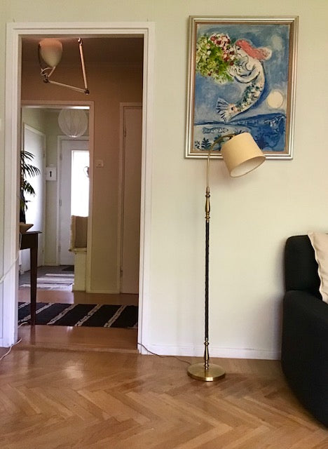 Living room with a lamp, painting, and open door to another room.