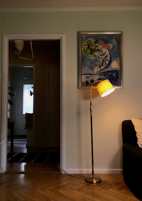 Living room with a lamp, painting on the wall, and a doorway leading to another room.