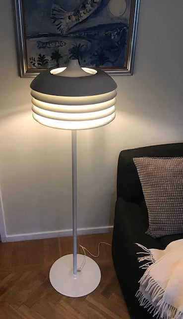 Modern floor lamp in a living room setting with a sofa and decorative pillow.
