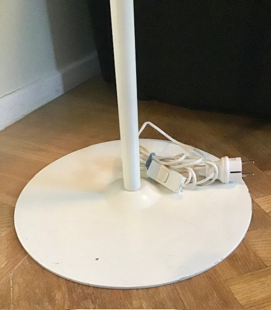 White lamp with a round base on a wooden floor