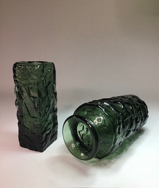 Two green textured glass bottles on a light background