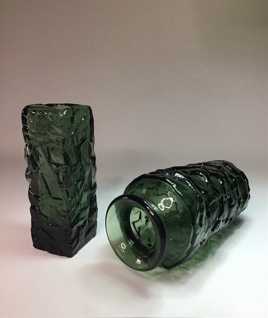 Two green textured glass bottles on a light background