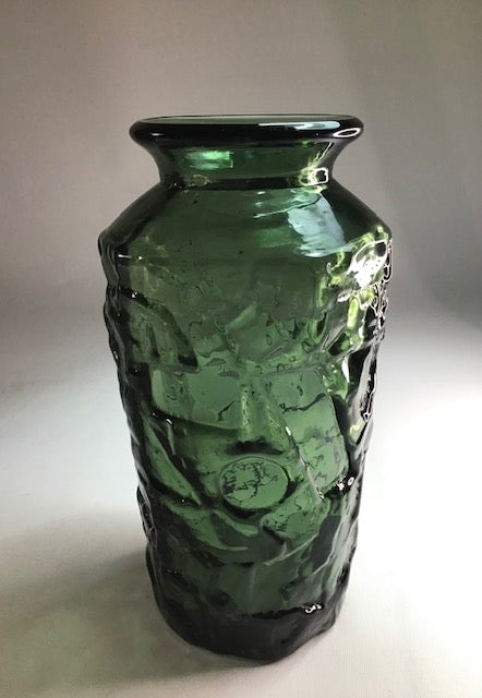 Green glass vase with textured surface on a white background