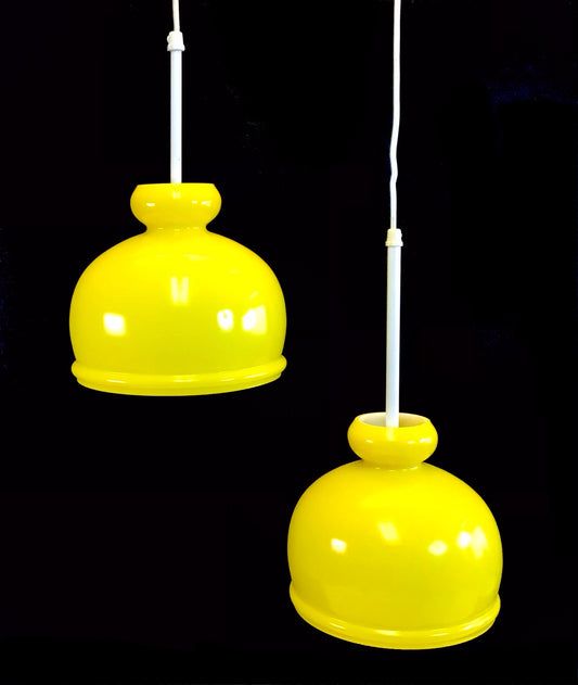 Two yellow pendant lights hanging against a black background