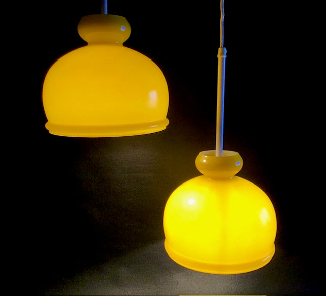 Two yellow pendant lights hanging against a dark background