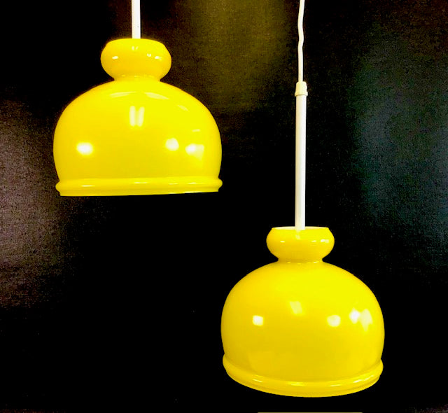 Two yellow pendant lights against a black background