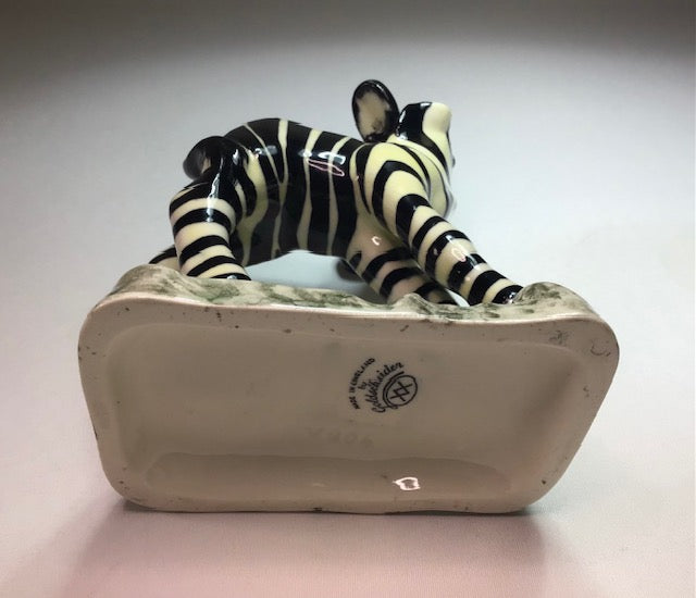 Ceramic zebra figurine on a white base with a gray background