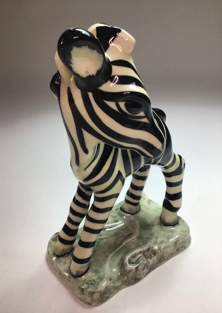 Zebra figurine on a decorative base against a plain background