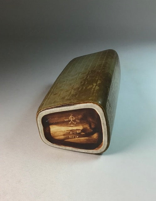 Rectangular ceramic object with a textured surface on a gray background