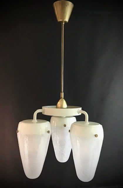Vintage chandelier with white glass shades and brass accents on a dark background