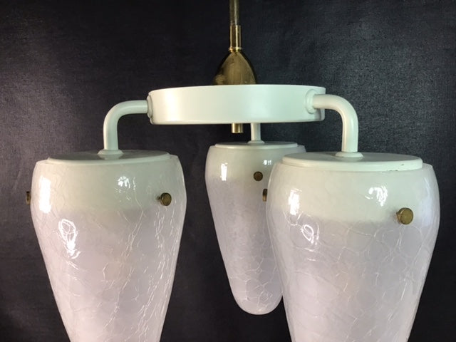 Vintage-style chandelier with three white glass shades on a dark background
