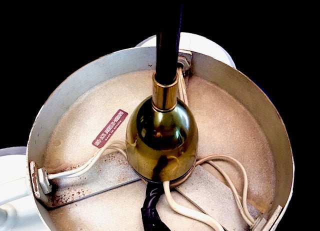 Close-up of a light bulb inside a lampshade with visible wear and tear.