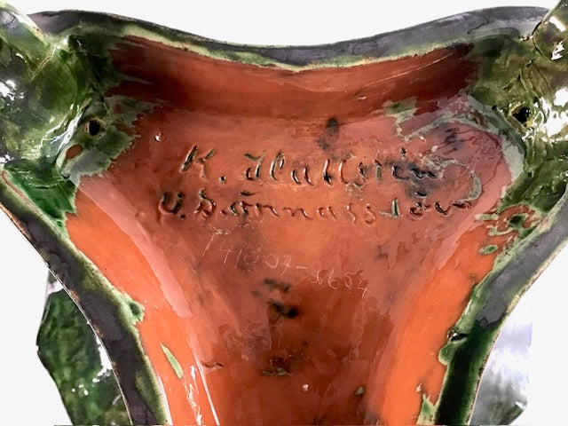 Ceramic dish with green rim and red-orange center, featuring engraved text.