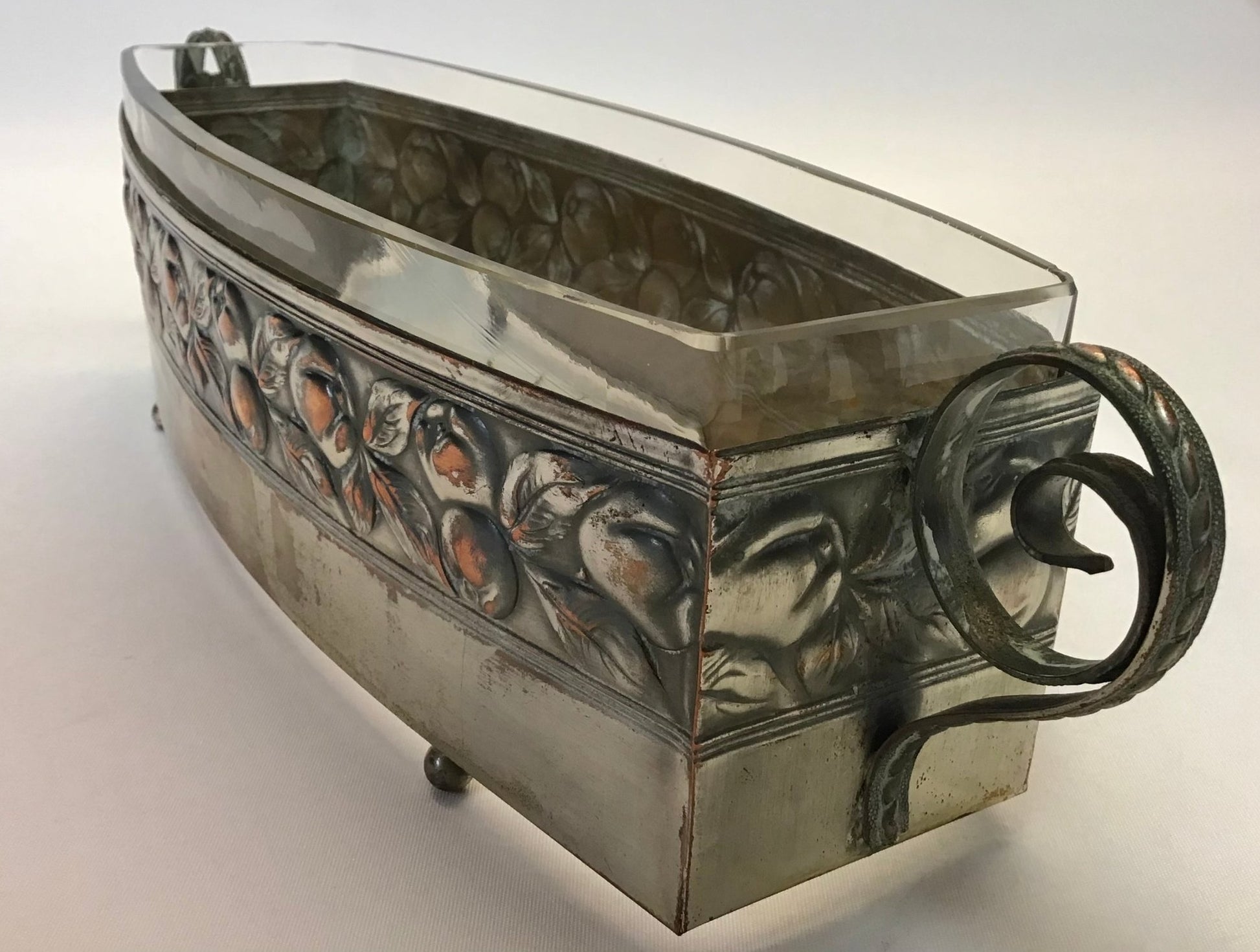 Decorative metal container with floral patterns and a handle on a white background