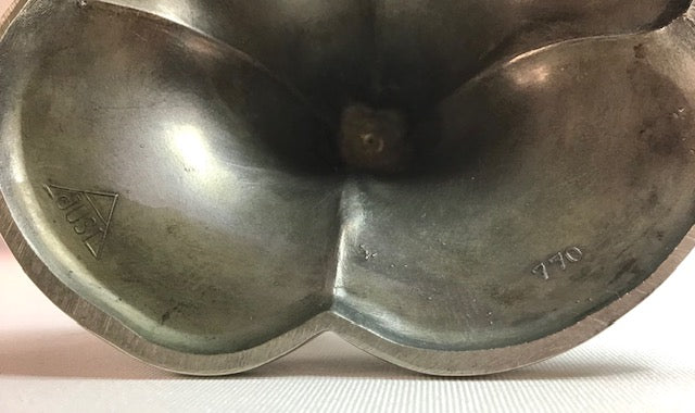 Bronze fruit-shaped object with engraved details on a white background