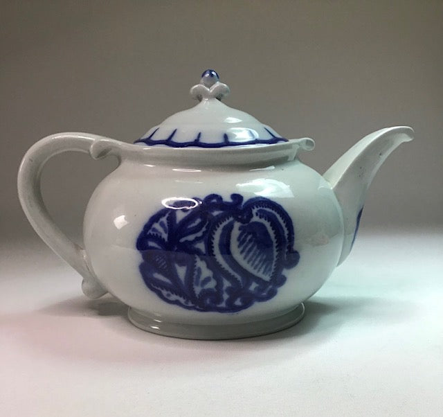 White teapot with blue floral patterns on a gray background