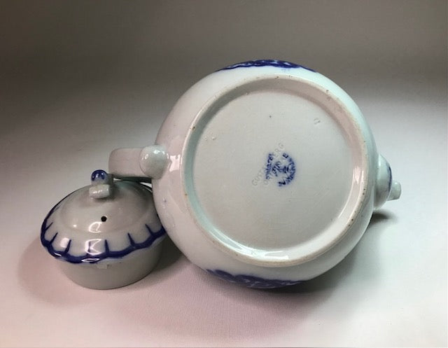 Ceramic teapot with blue decorative elements on a plain background