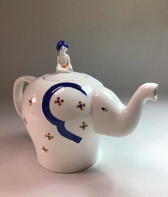 Teapot with elephant design and character on top against a plain background