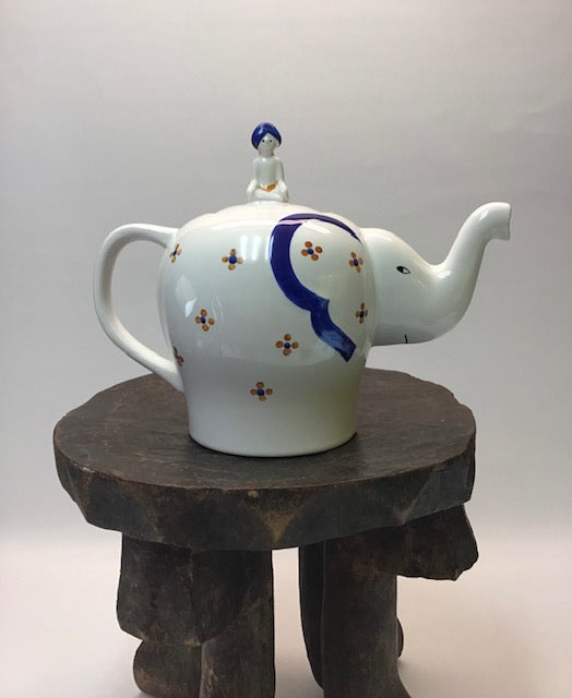 Decorative teapot with floral patterns on a wooden stand against a white background
