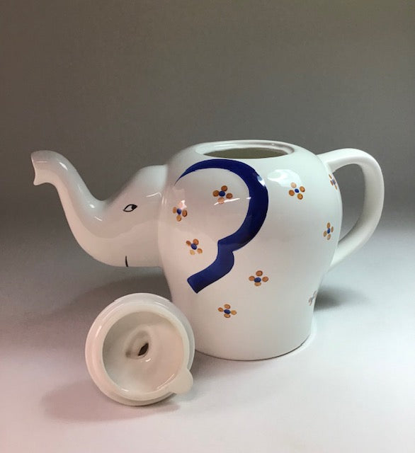 White ceramic teapot with blue design on a light gray background