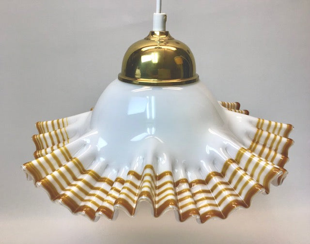 Pendant light with white glass shade and gold ruffled edge on a plain background
