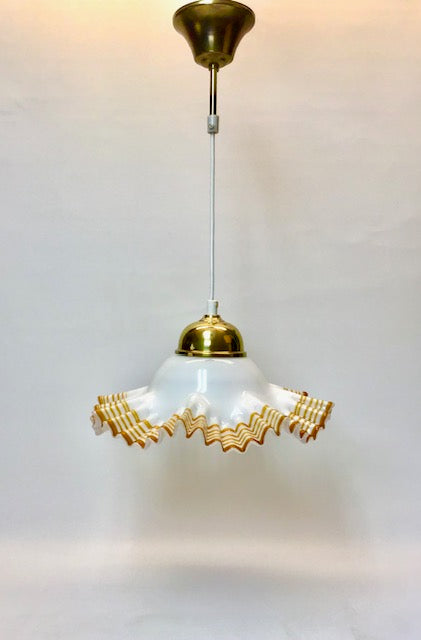 Pendant light with white glass shade and gold decorative elements on a plain background
