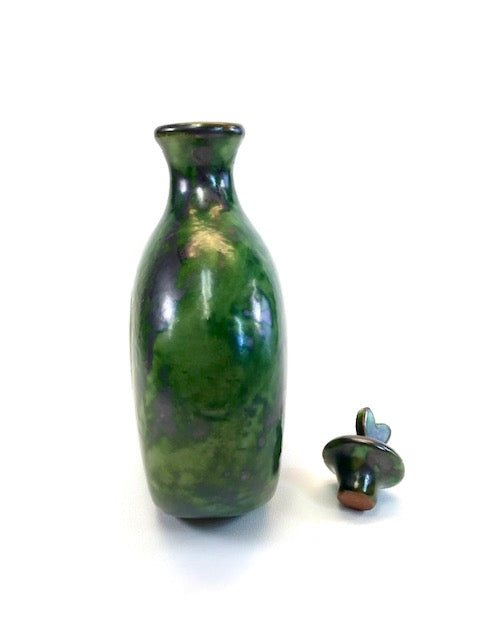 Green ceramic bottle with a matching cap on a white background