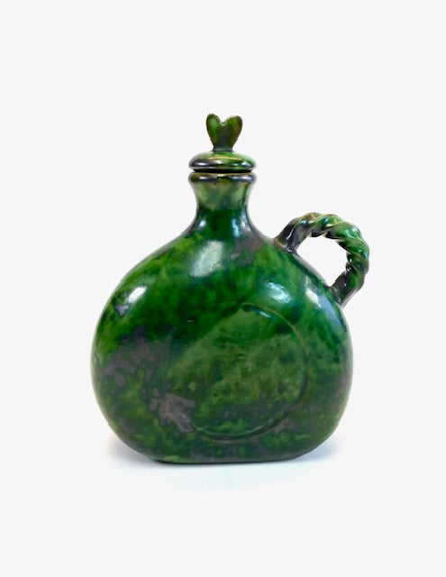 Green ceramic jug with a lid on a white background