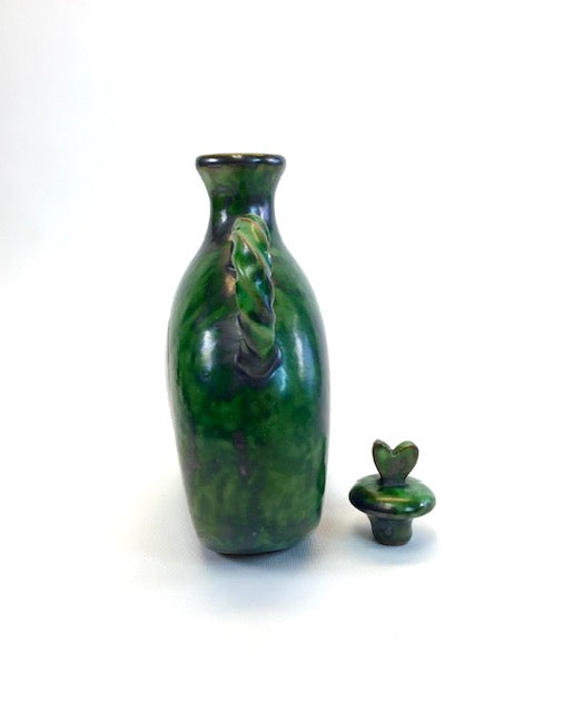 Green ceramic bottle with a lid on a white background