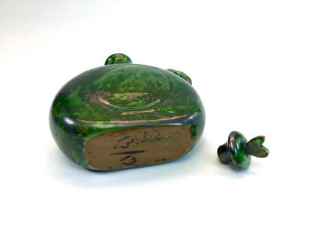 Green ceramic frog-shaped container with a lid on a white background