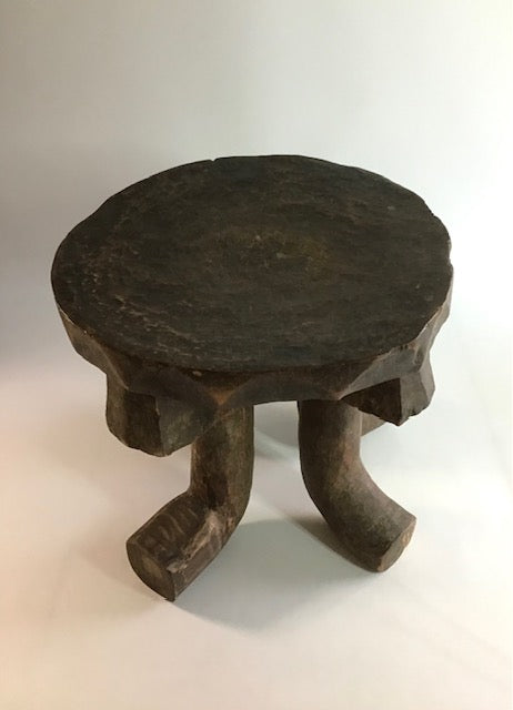 Wooden stool with a round top and four legs on a white background