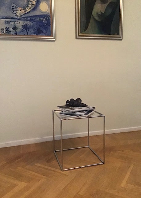 Glass side table with decorative items against a wall with framed artwork