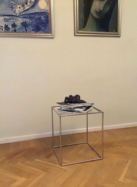 Glass side table with decorative items against a wall with framed artwork