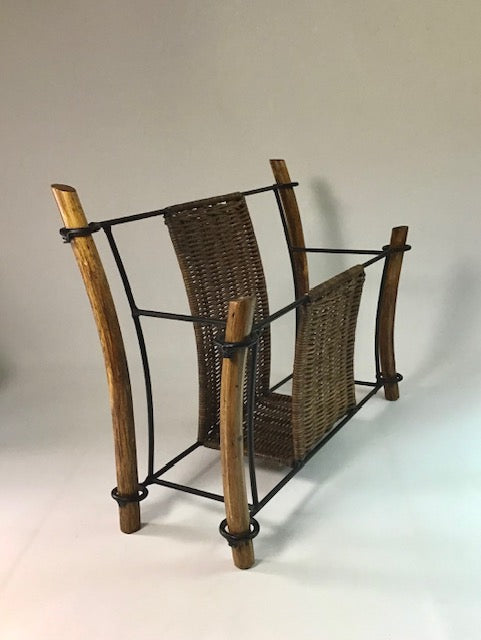 Wicker magazine rack with metal straps on a plain background