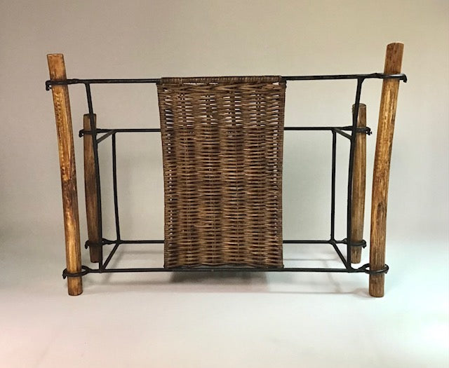 Wicker basket inside a metal frame with wooden legs on a plain background
