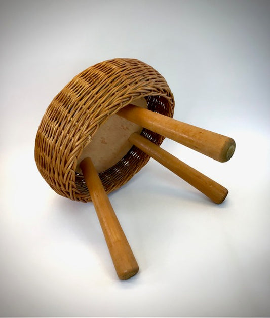 Wicker stool with wooden legs on a white background