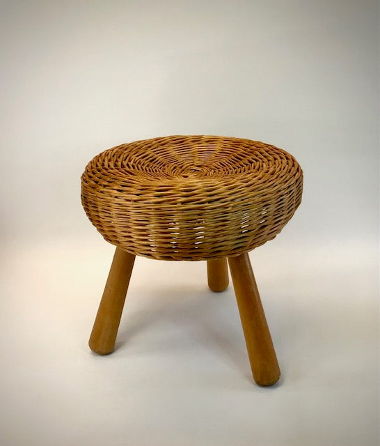 Wicker stool with wooden legs on a plain background